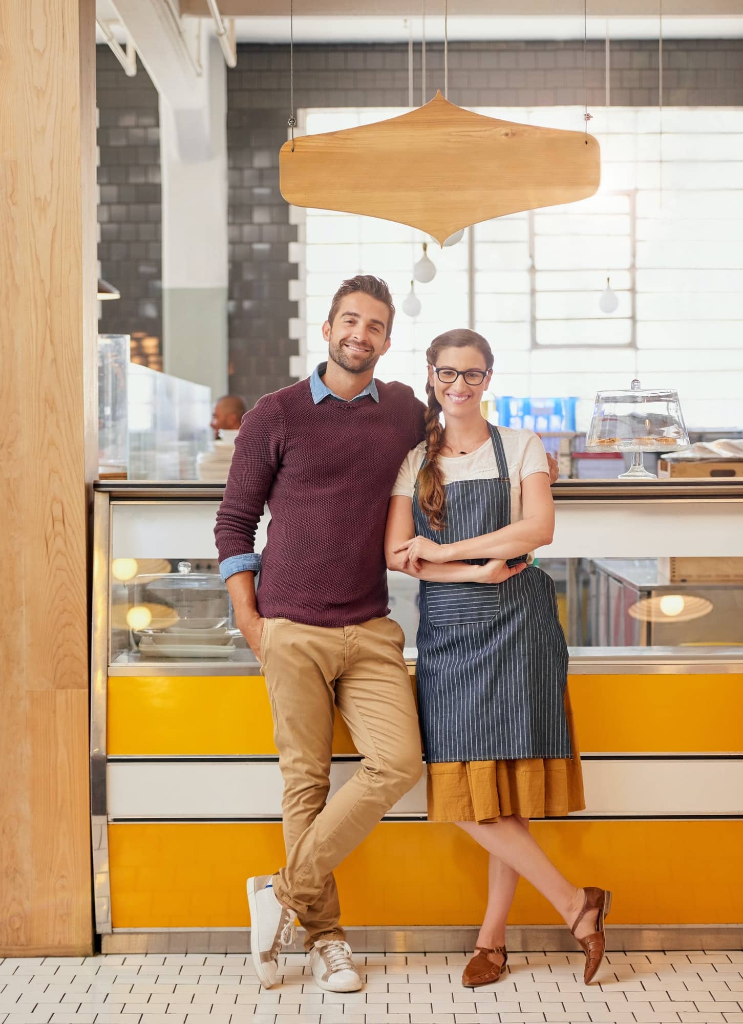 Portrait of two young business owners posing in front of the counter in their coffee shop