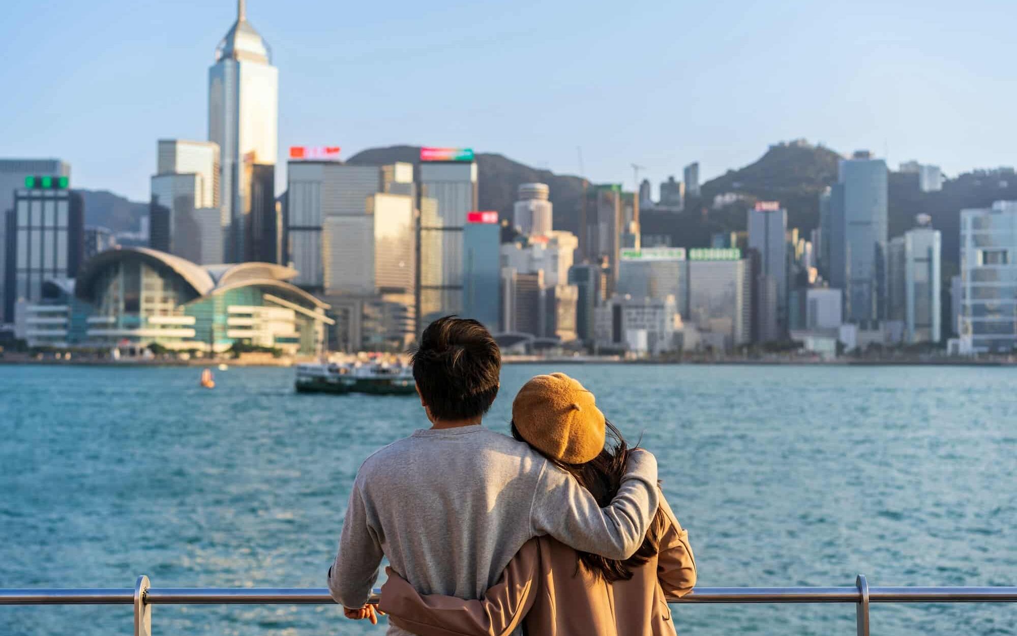 Young couple traveler relaxing and enjoying the sunset atmosphere at Victoria harbour in Hong Kong